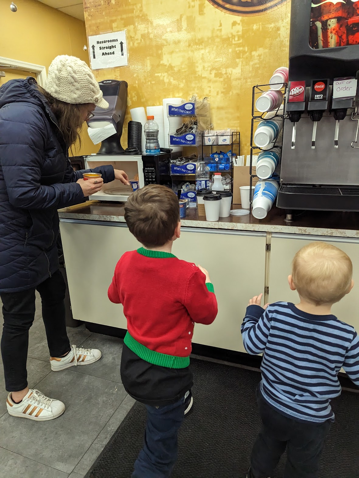a woman and two children standing in front of a coffee machine