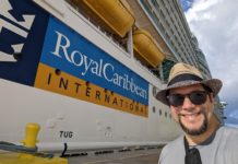 a man in a hat and sunglasses standing in front of a large cruise ship