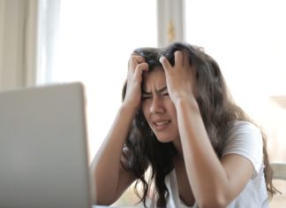 a woman holding her head in front of a laptop