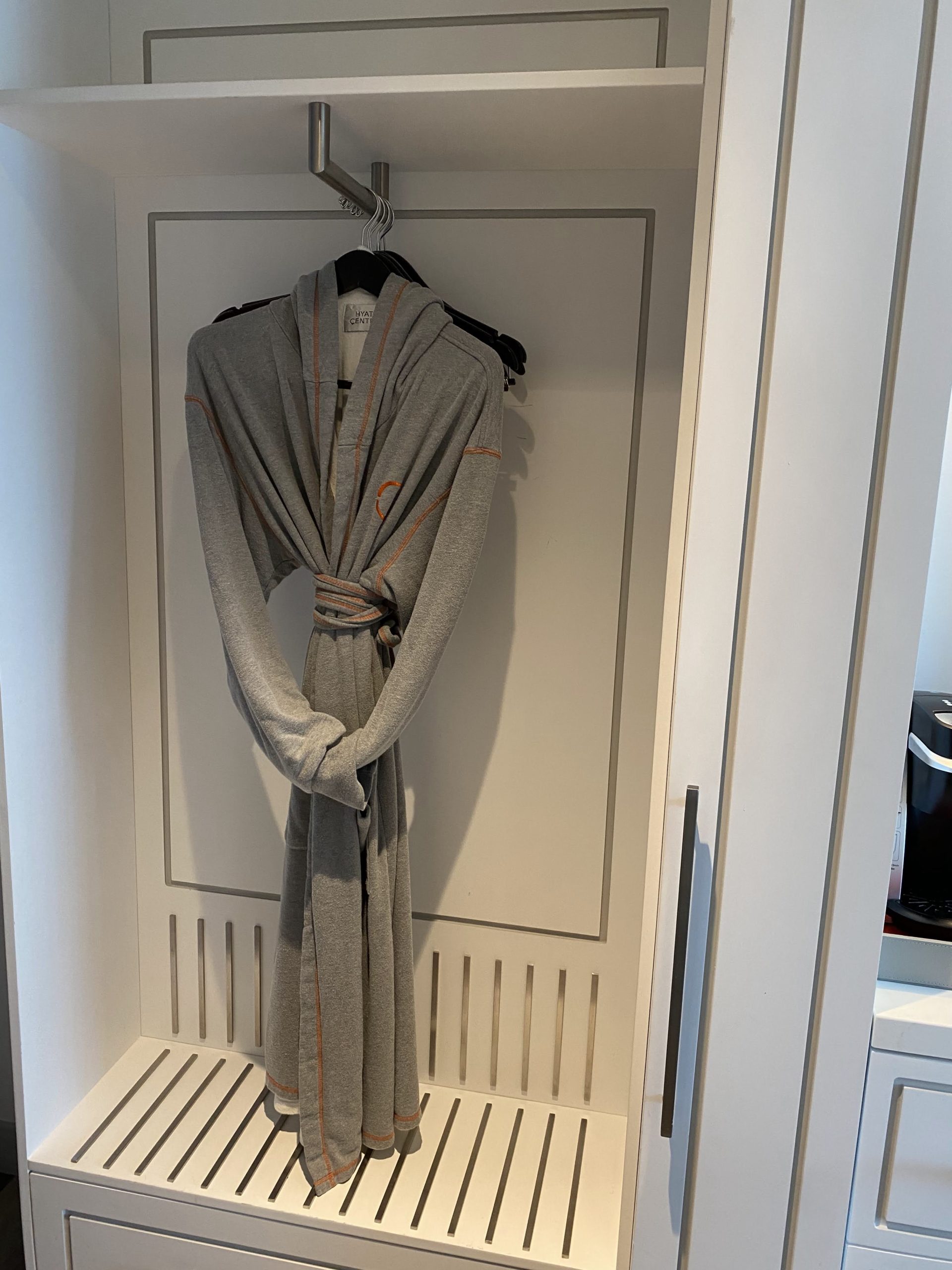 a grey robe on a swinger in a closet