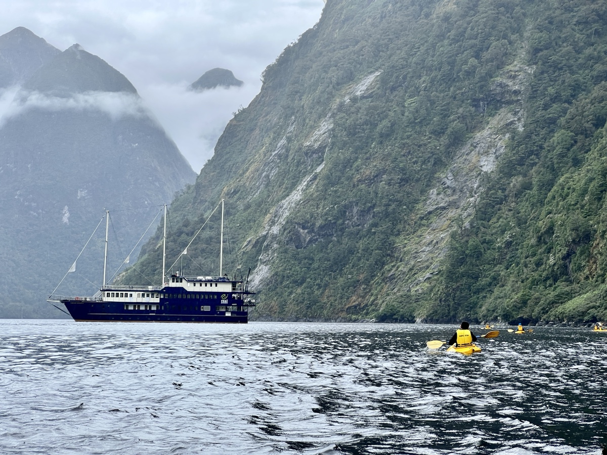 a boat in the water with mountains in the background with Milford Sound in the background