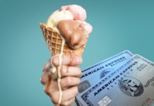 a hand holding a waffle cone with ice cream and two american express cards