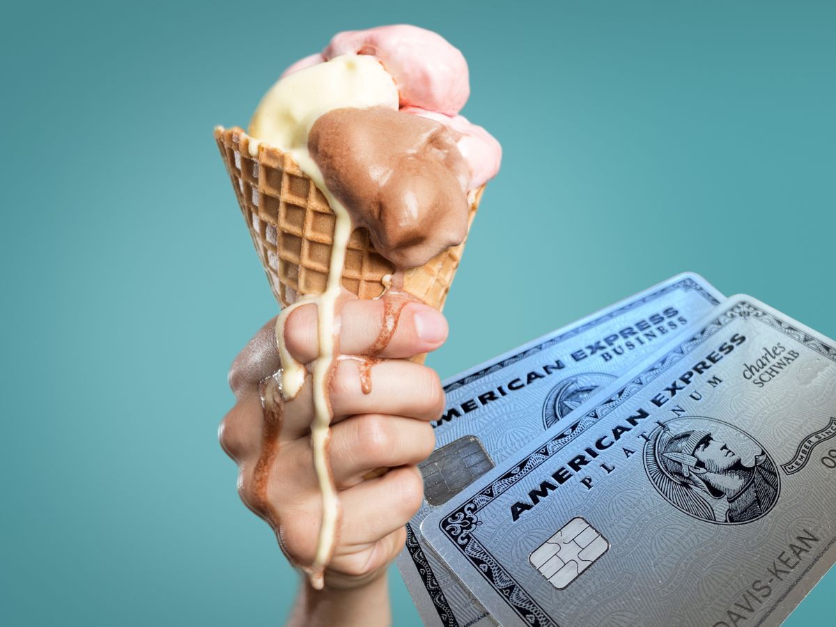 a hand holding a waffle cone with ice cream and two american express cards