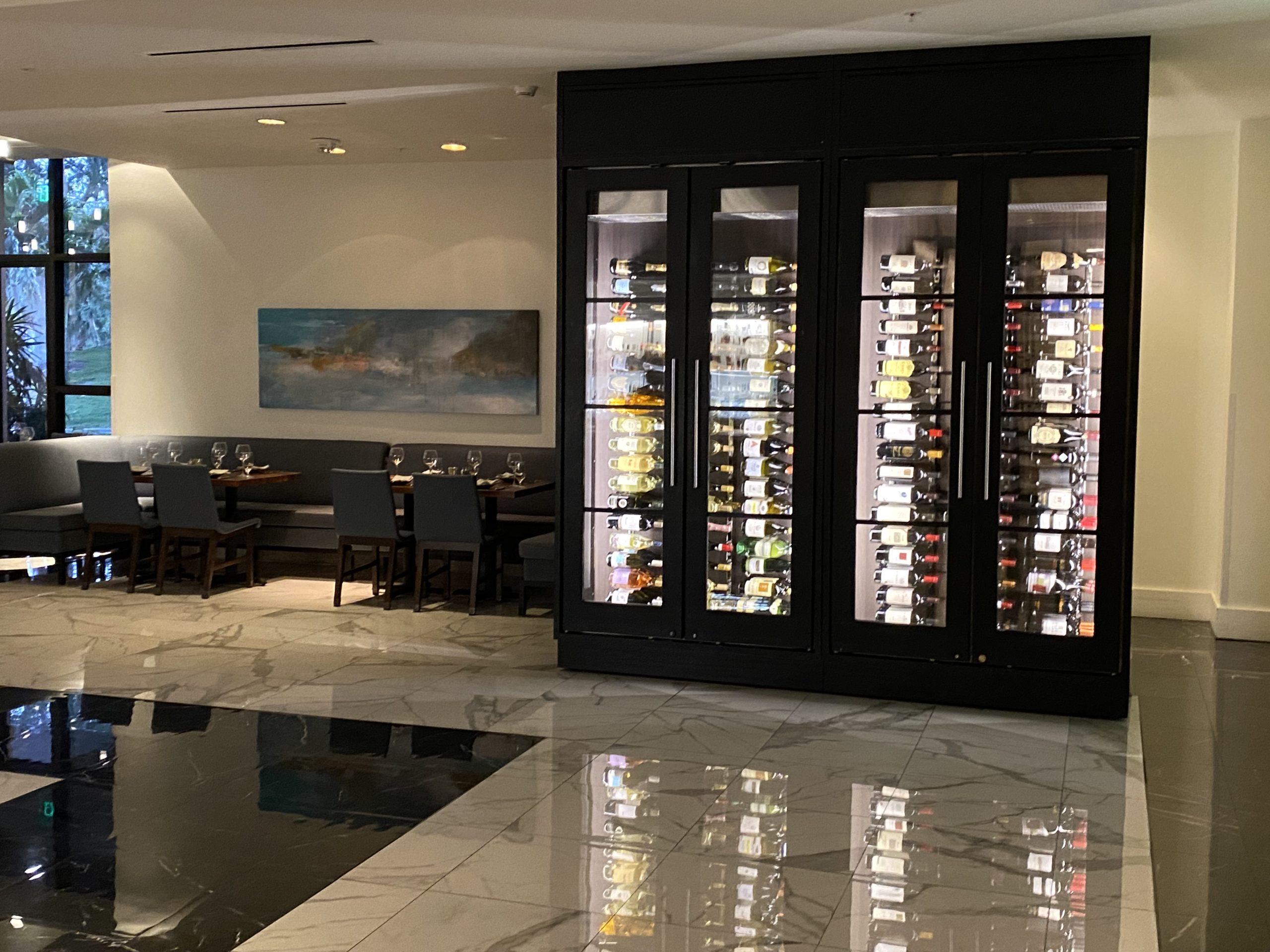 a room with a glass cabinet with wine bottles in it
