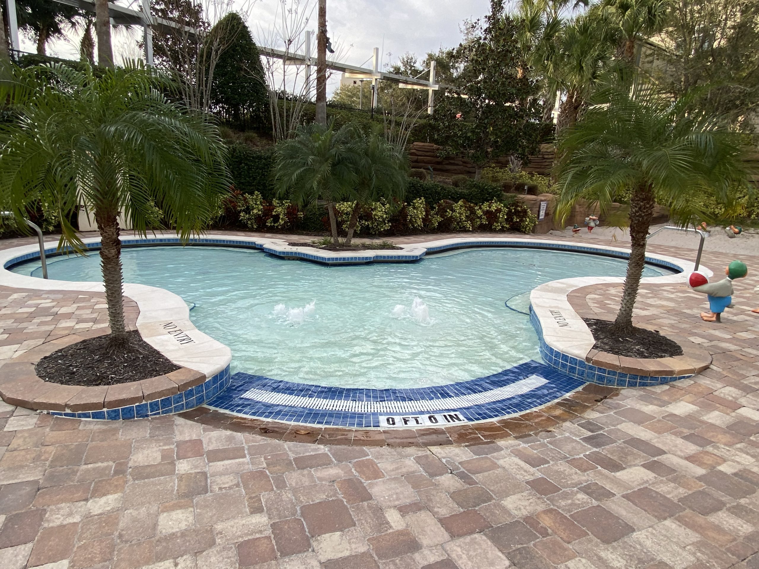 a pool with palm trees and a stone walkway
