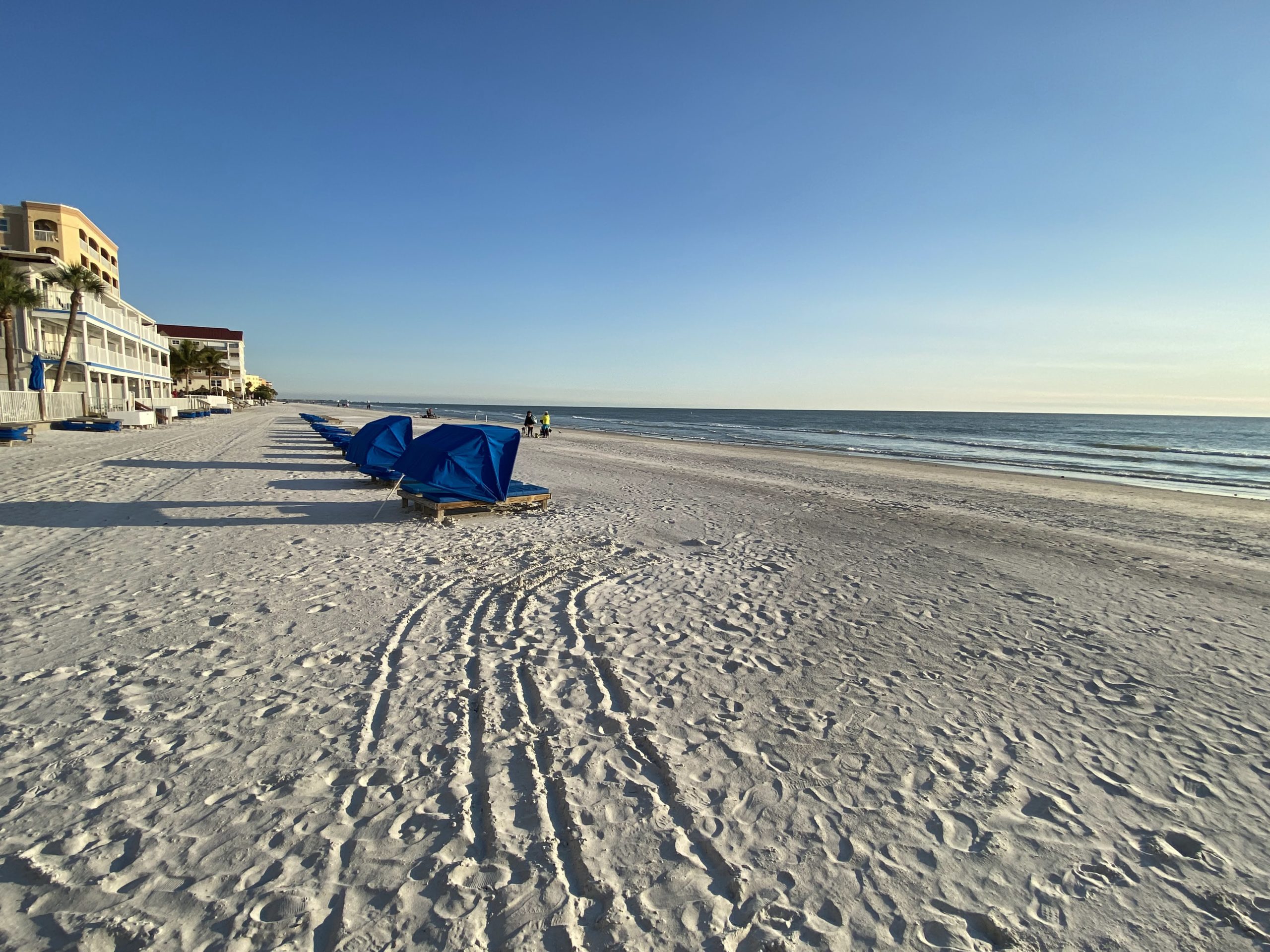 a beach with blue chairs and a blue tent