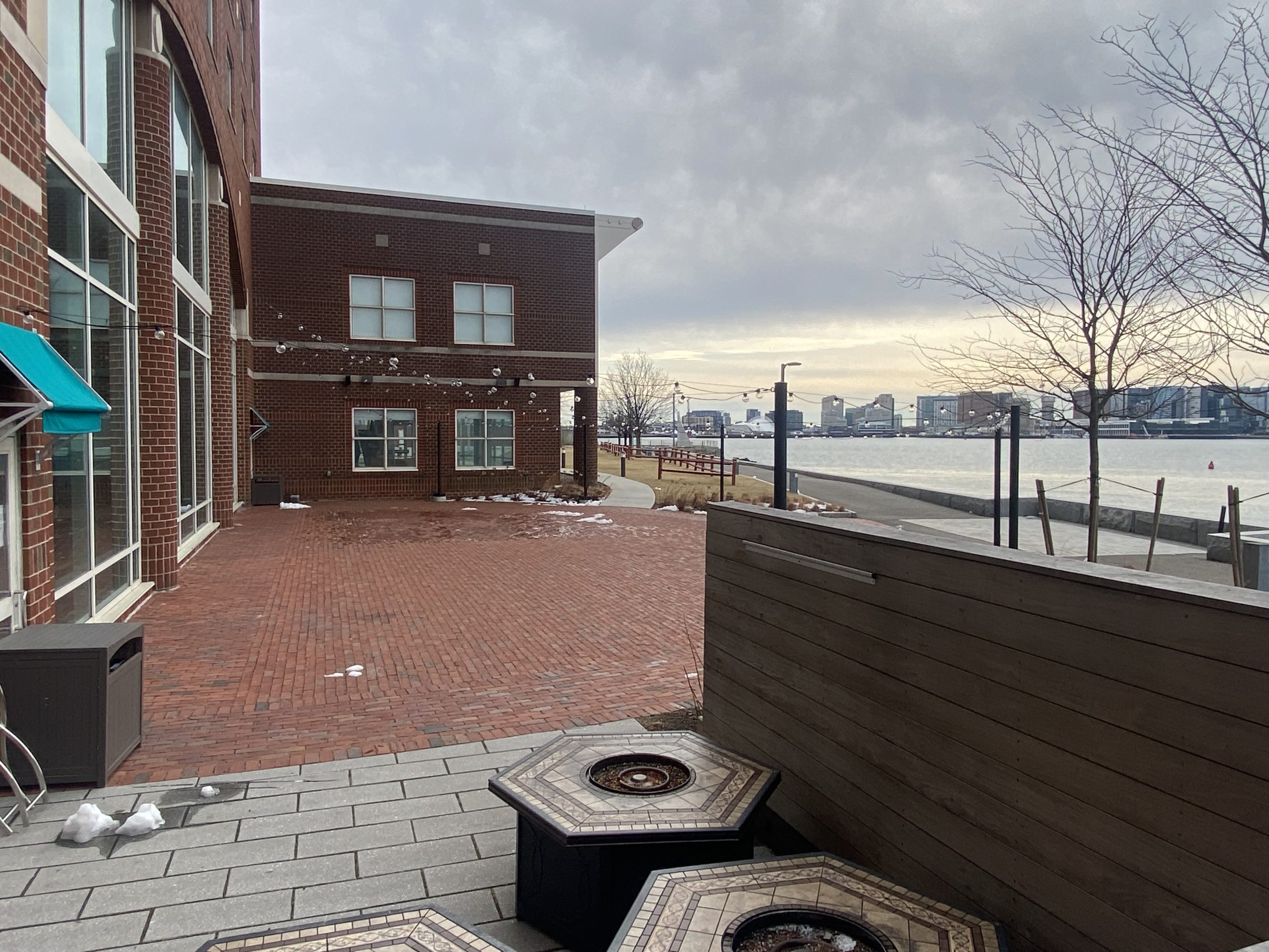 a brick patio with a building and a body of water in the background