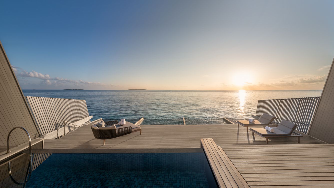 a deck with chairs and a pool overlooking the ocean