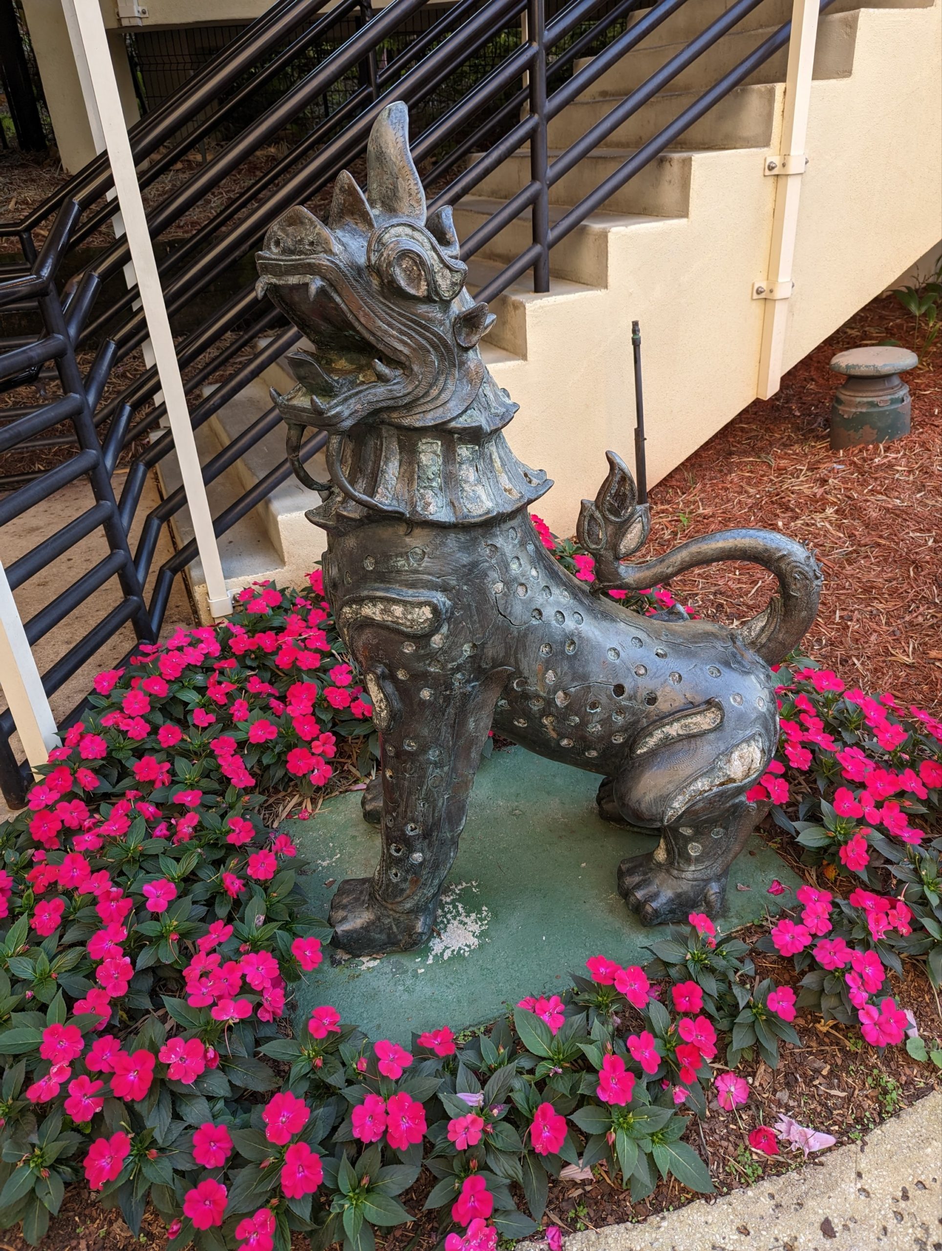 a statue of a dragon in a flower bed