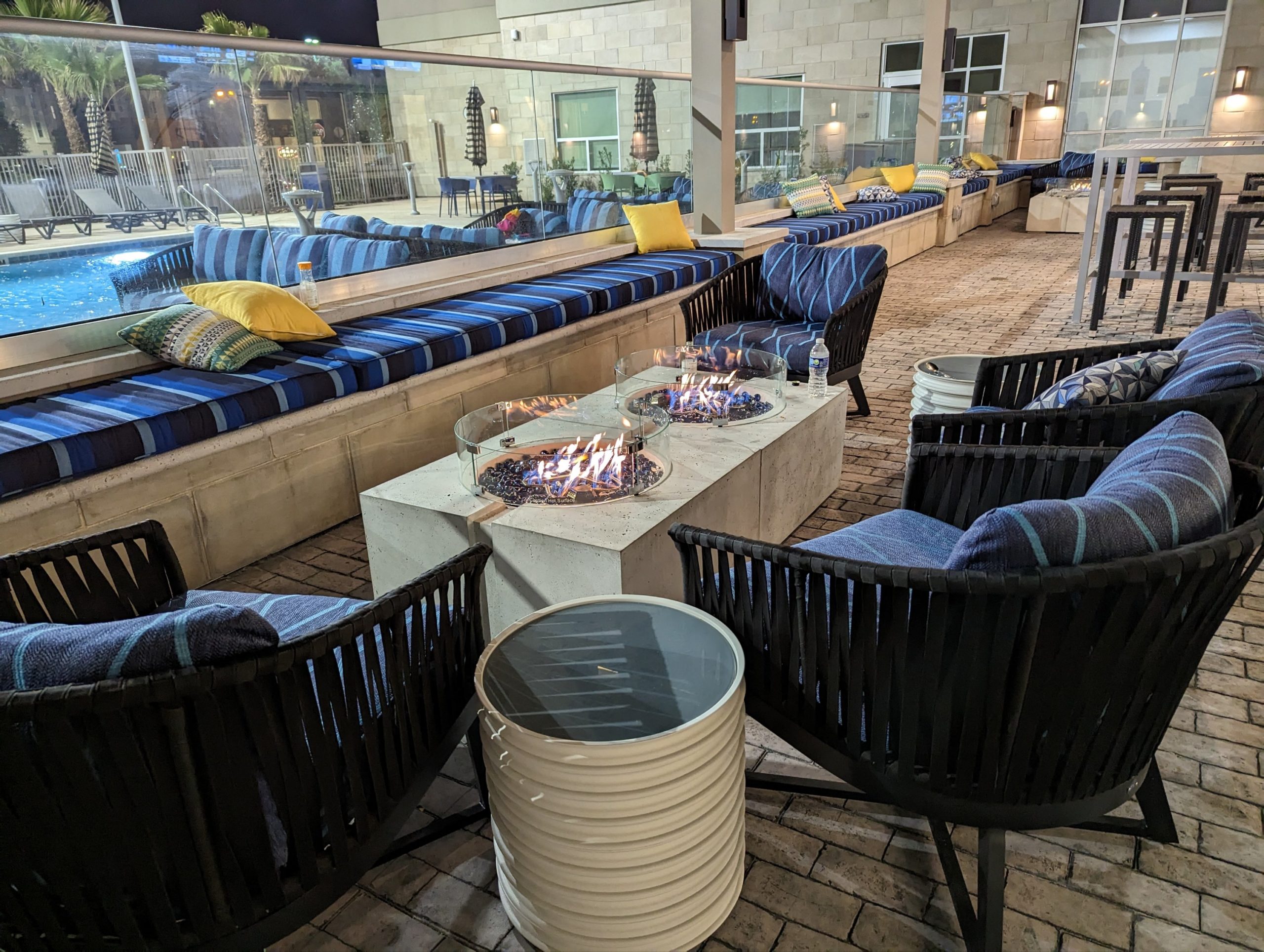 a fire pit with chairs and pillows on a patio