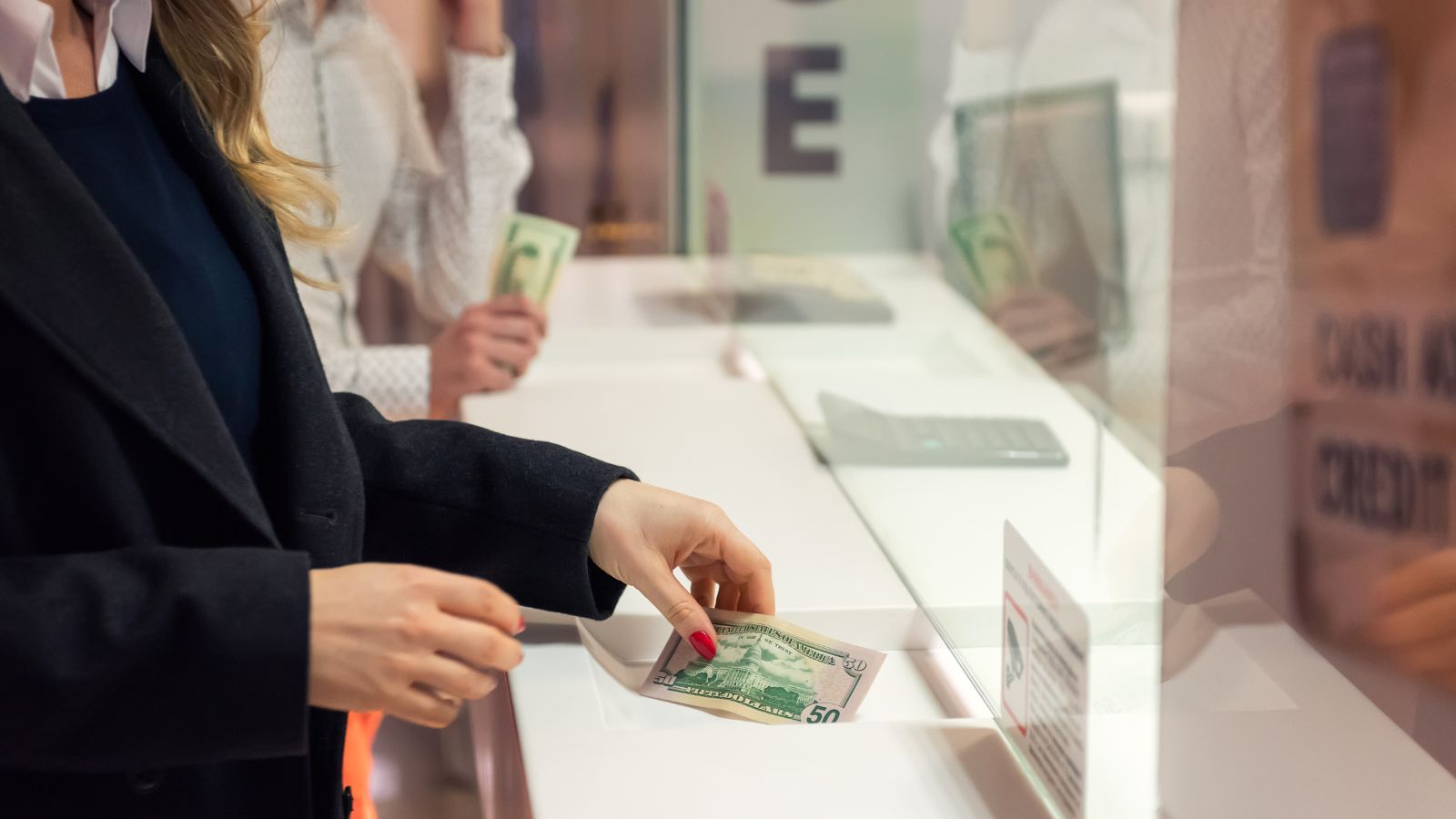 a woman holding money in a glass case