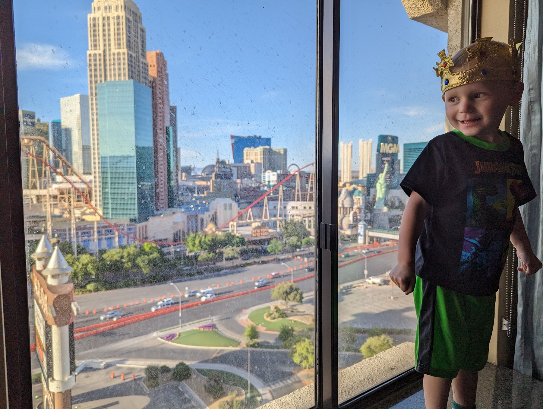 a boy standing in front of a window with a city in the background