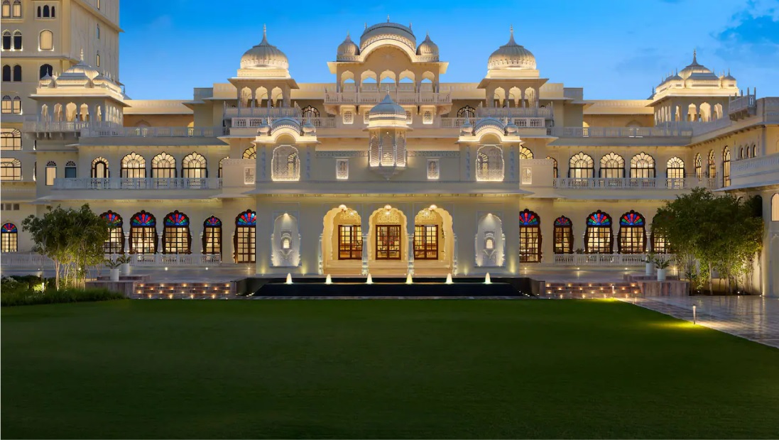 a large white building with a lawn and lights