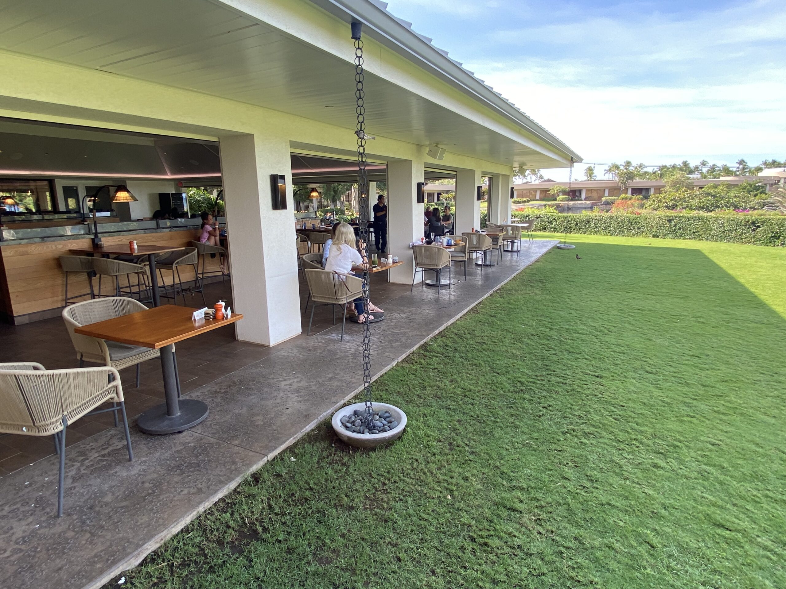 a group of people sitting at tables and chairs in a yard