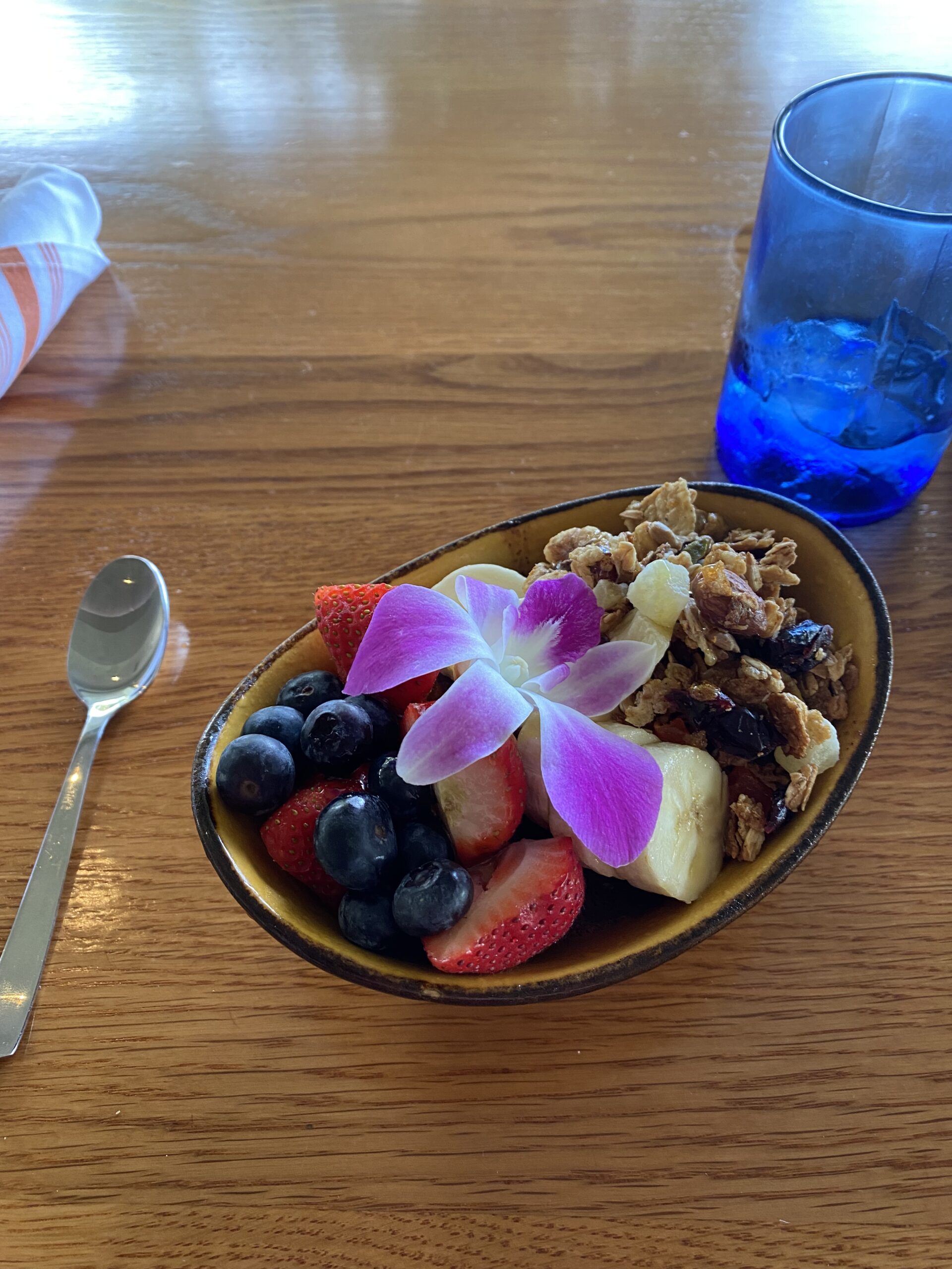 a bowl of fruit and a flower on a table