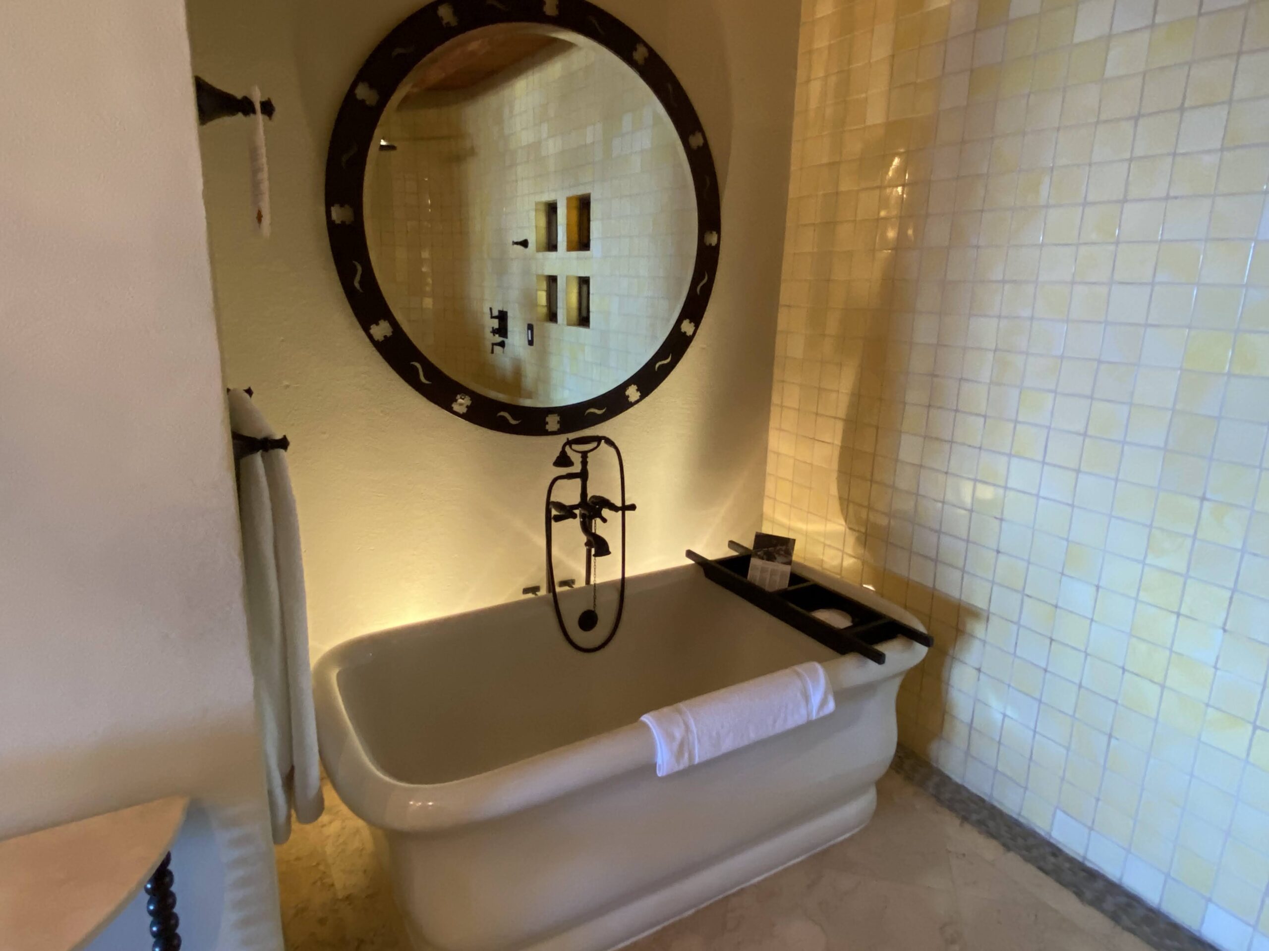 a bathroom with a tub and a round mirror