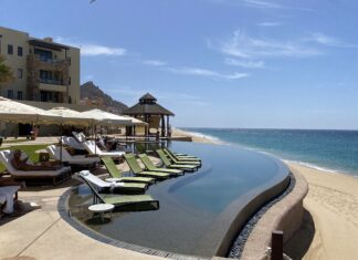 a pool with lounge chairs and umbrellas on the beach