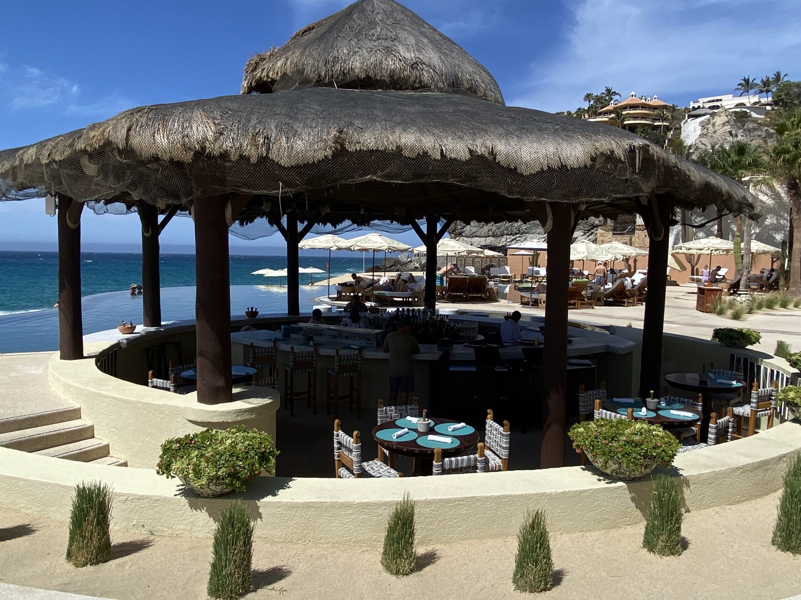 a beach bar with a thatched roof and tables
