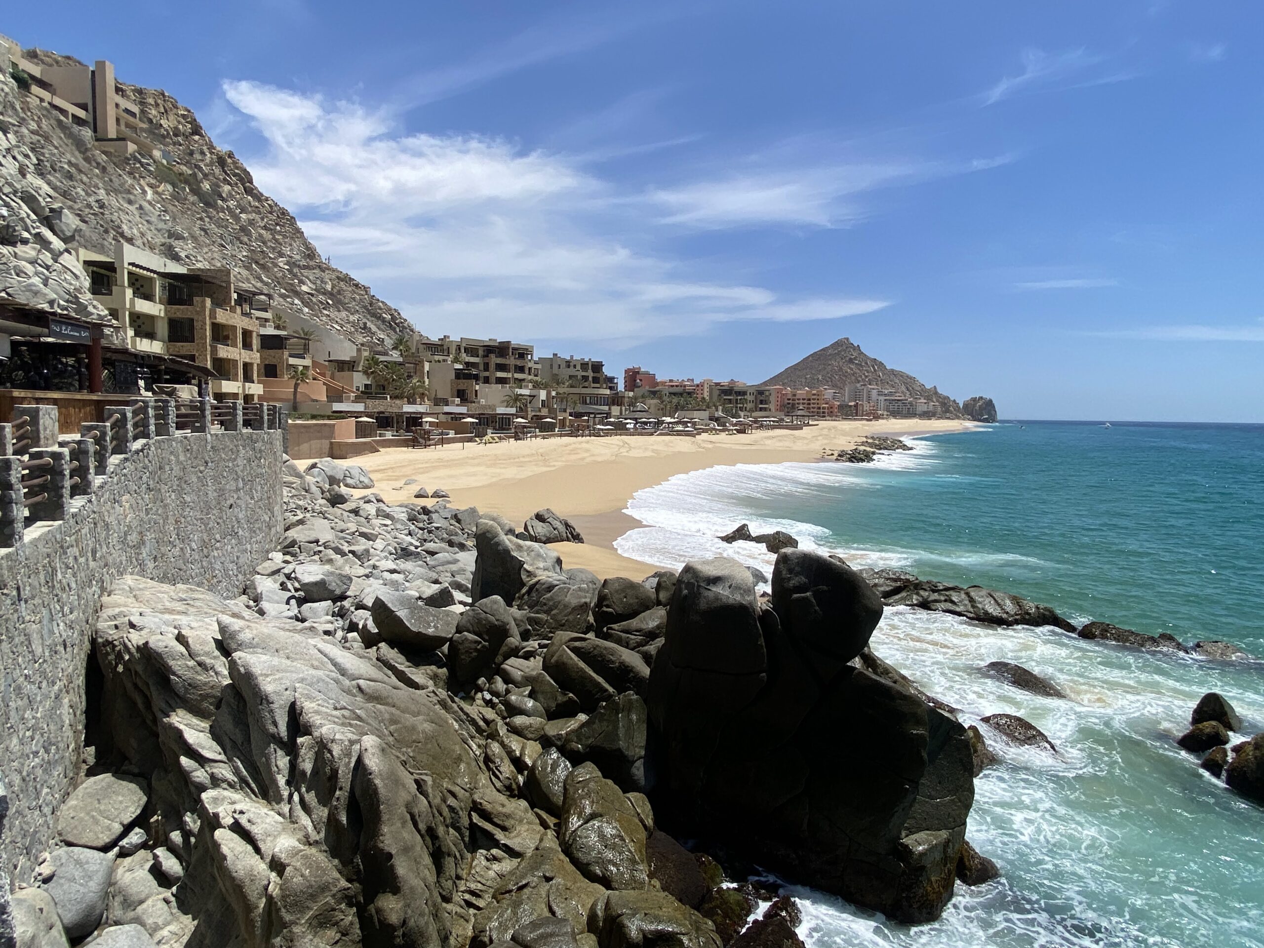 a rocky beach with buildings and a body of water