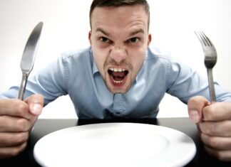 a man with a knife and fork in front of a plate