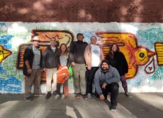 a group of people posing for a photo in front of a mural