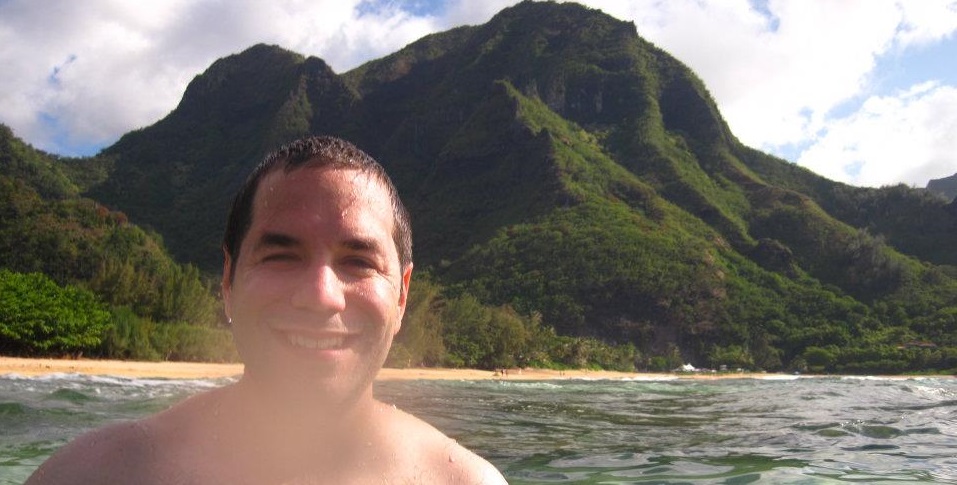 a man smiling in front of a mountain