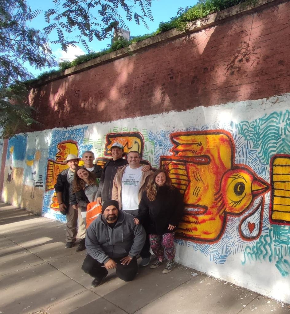 a group of people posing for a photo in front of a wall with graffiti