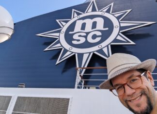 a man taking a selfie in front of a large blue and white sign