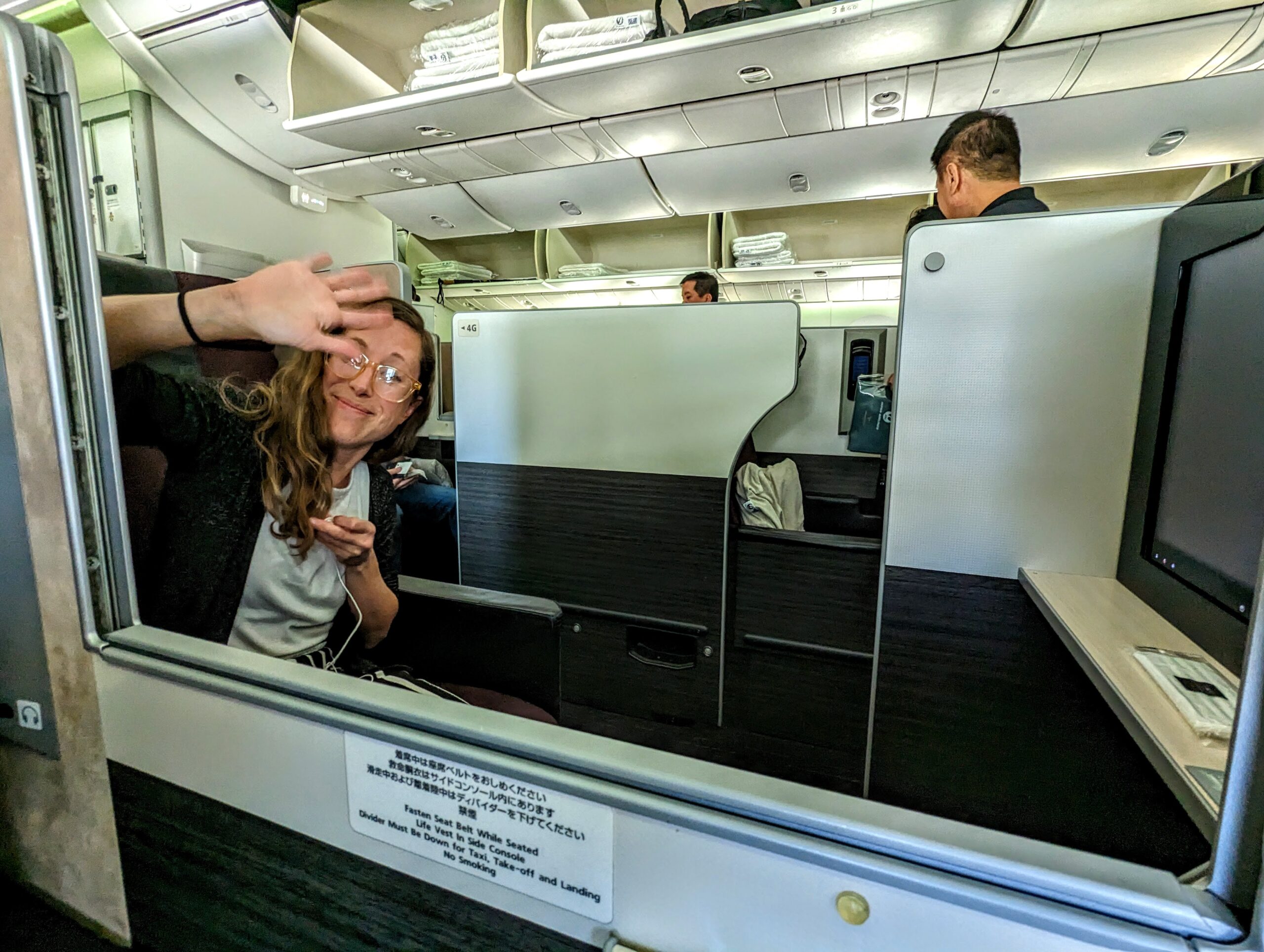 a woman sitting in an airplane with her hand up