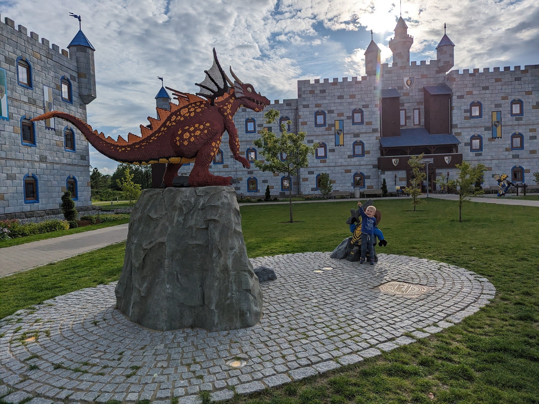 a child standing next to a statue of a dragon
