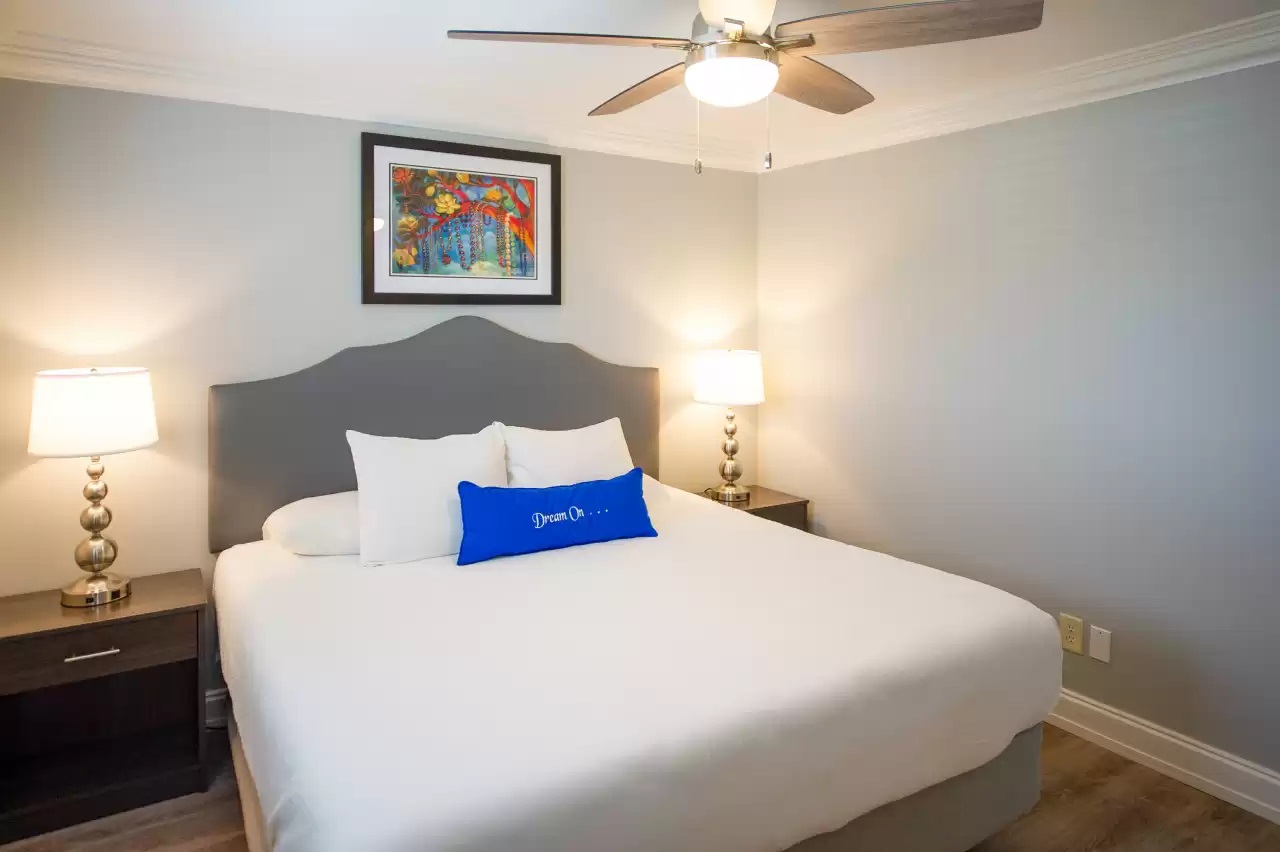 a bed with a fan and a picture on the wall