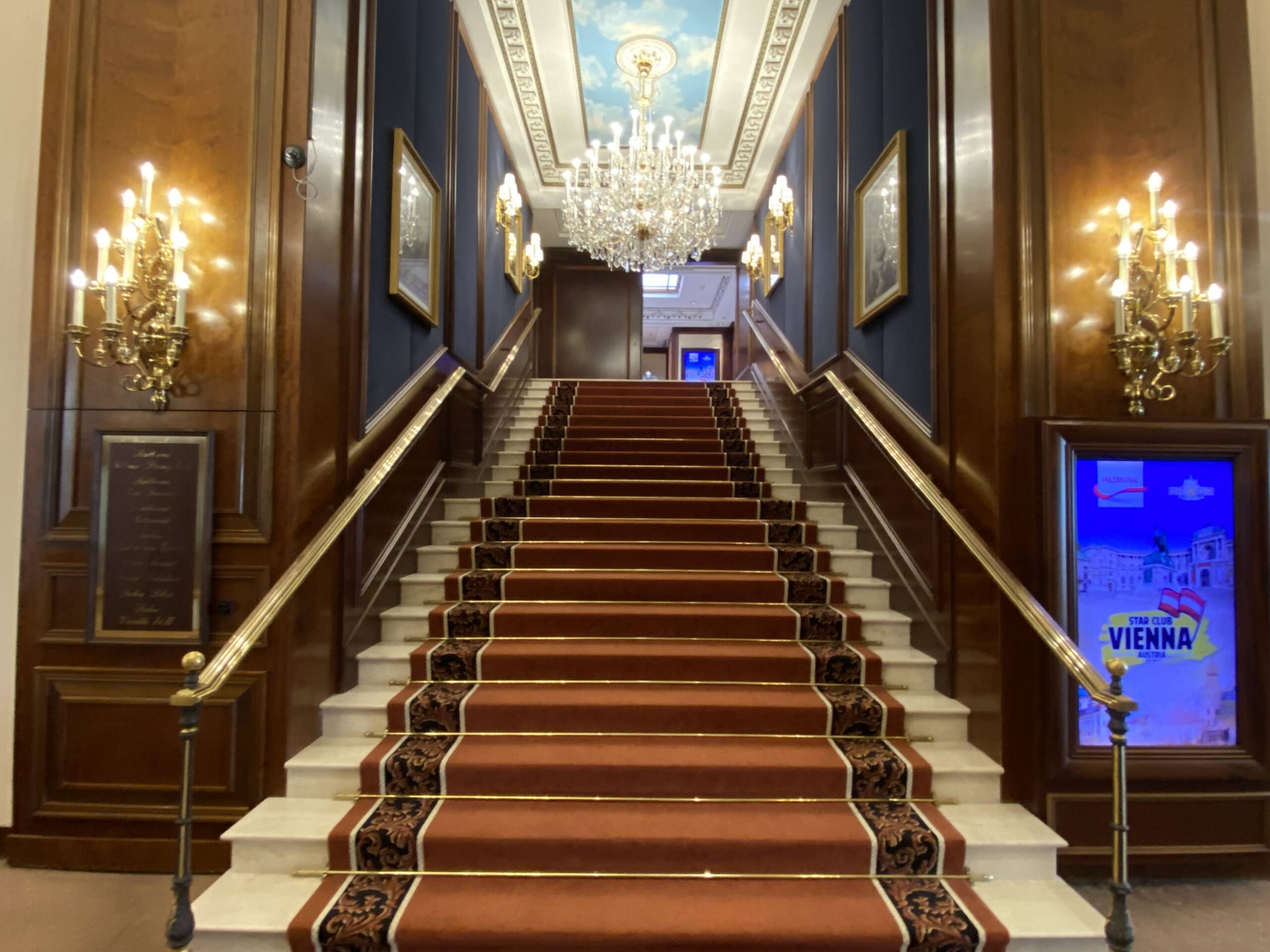a staircase with red carpet and chandeliers