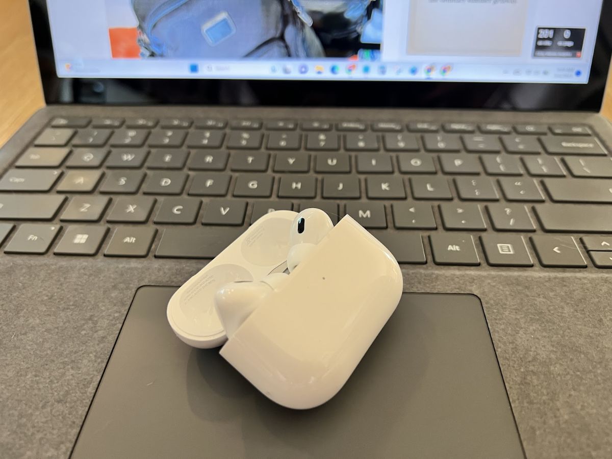 a white wireless earbuds on a laptop keyboard