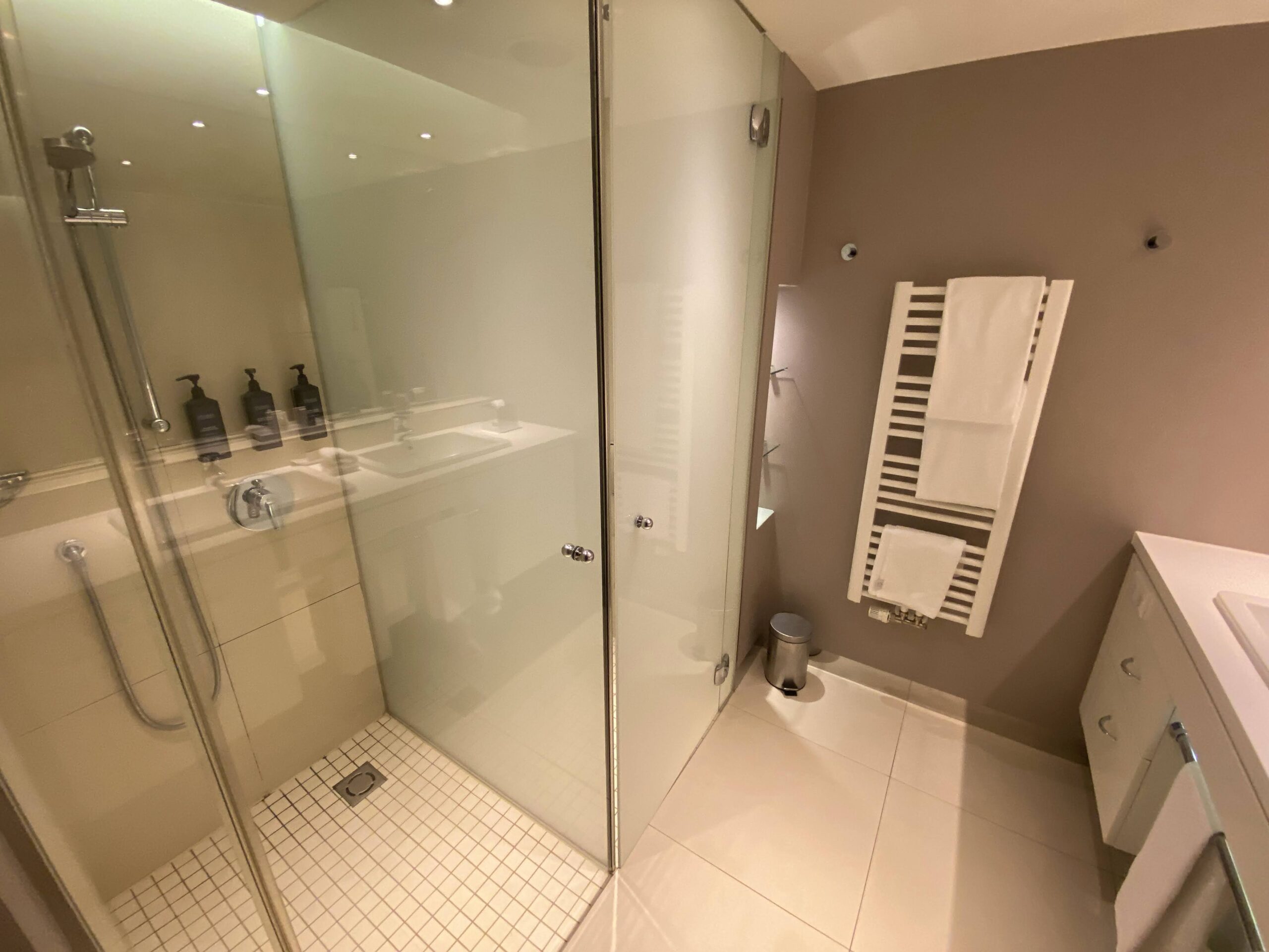 a bathroom with glass shower and white tile floor