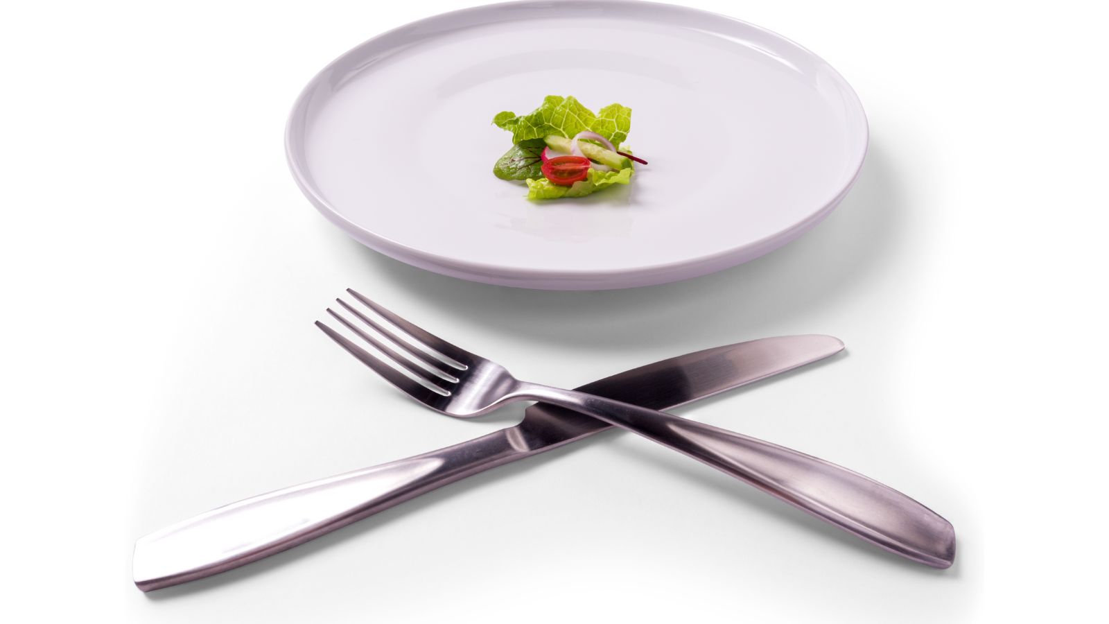 a plate with a small leafy vegetable on it next to a knife and fork