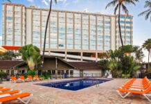 a pool with orange chairs and a building in the background