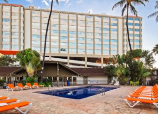 a pool with orange chairs and a building in the background