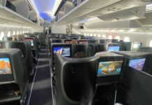 a row of seats with monitors on the back of an airplane