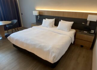 a bed with white sheets and pillows in a room