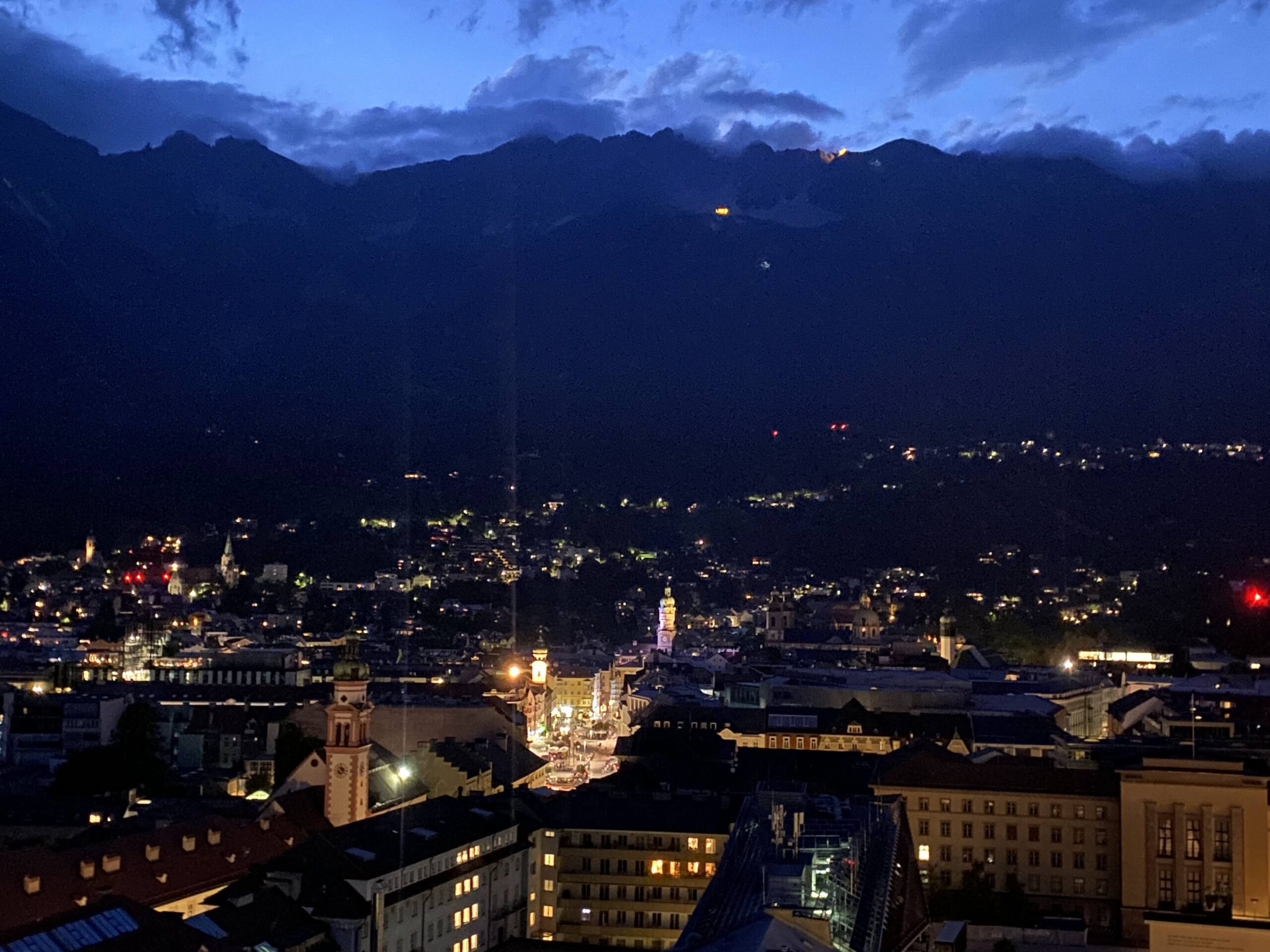 a city at night with mountains in the background