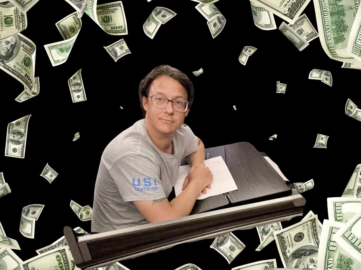 a man sitting at a desk with paper and money falling