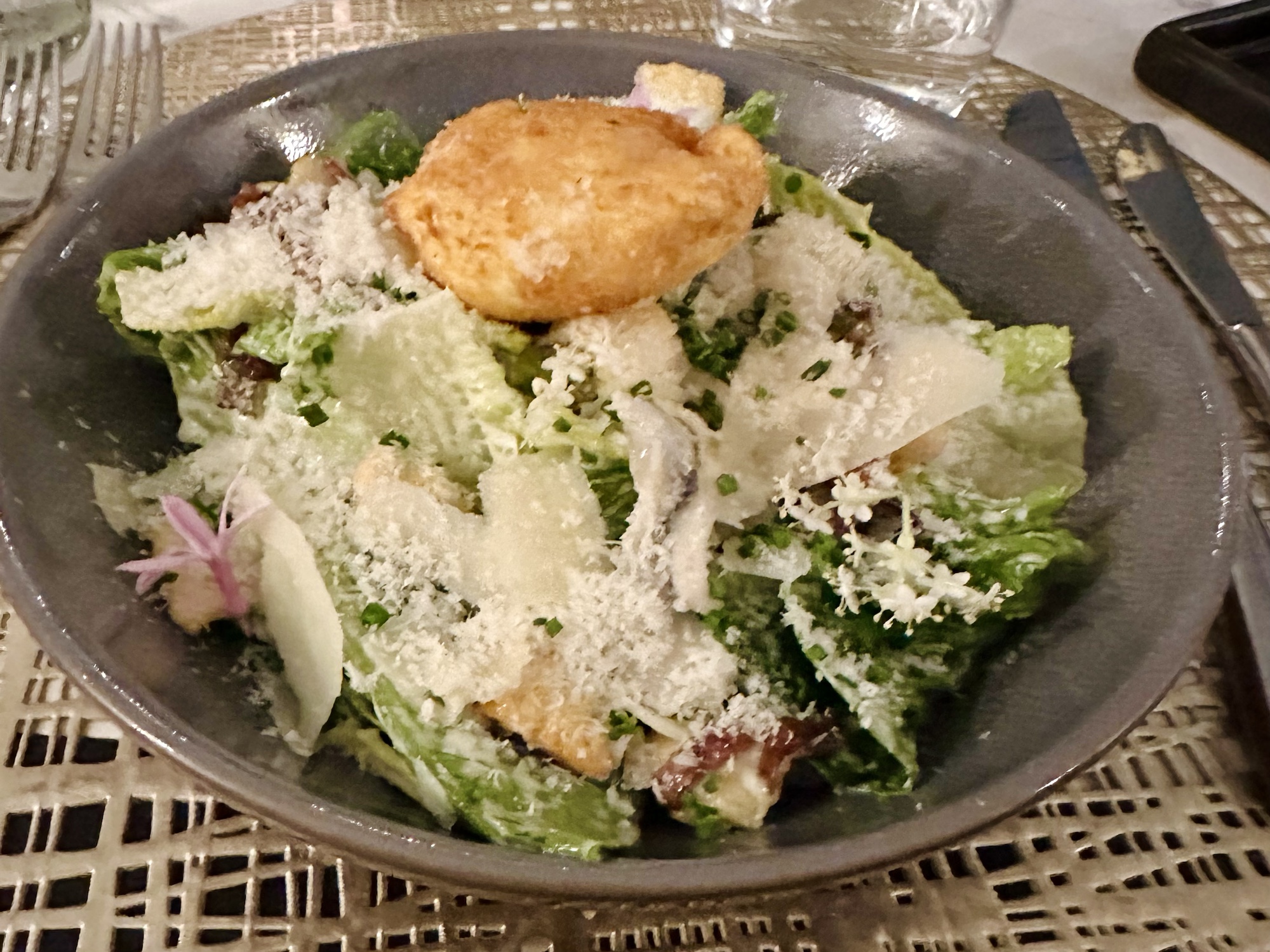 a bowl of salad with cheese and a piece of bread on top