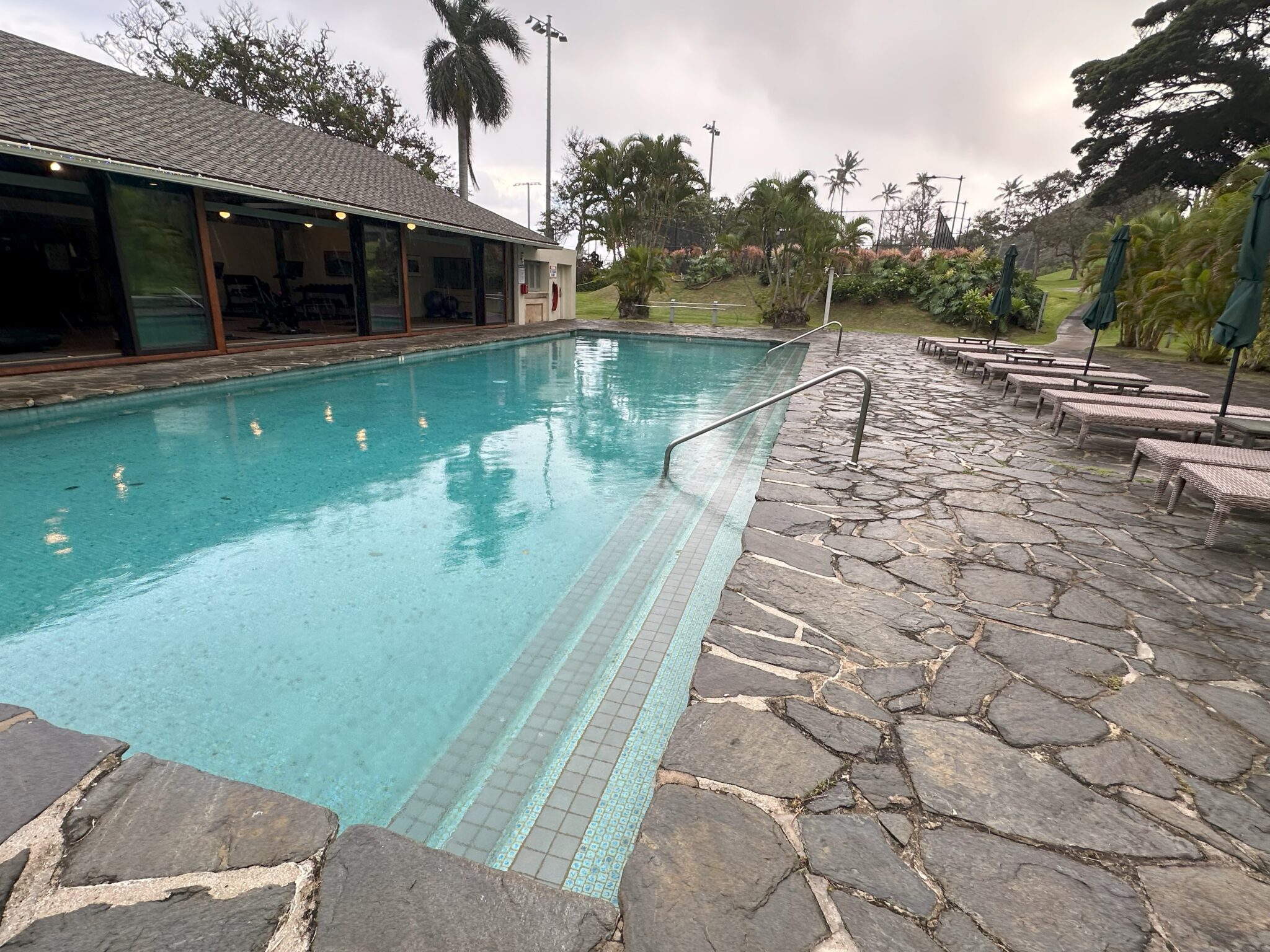 a pool with a stone walkway and a building