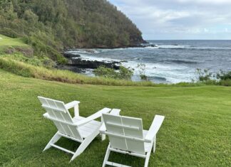 two white chairs on grass by the ocean