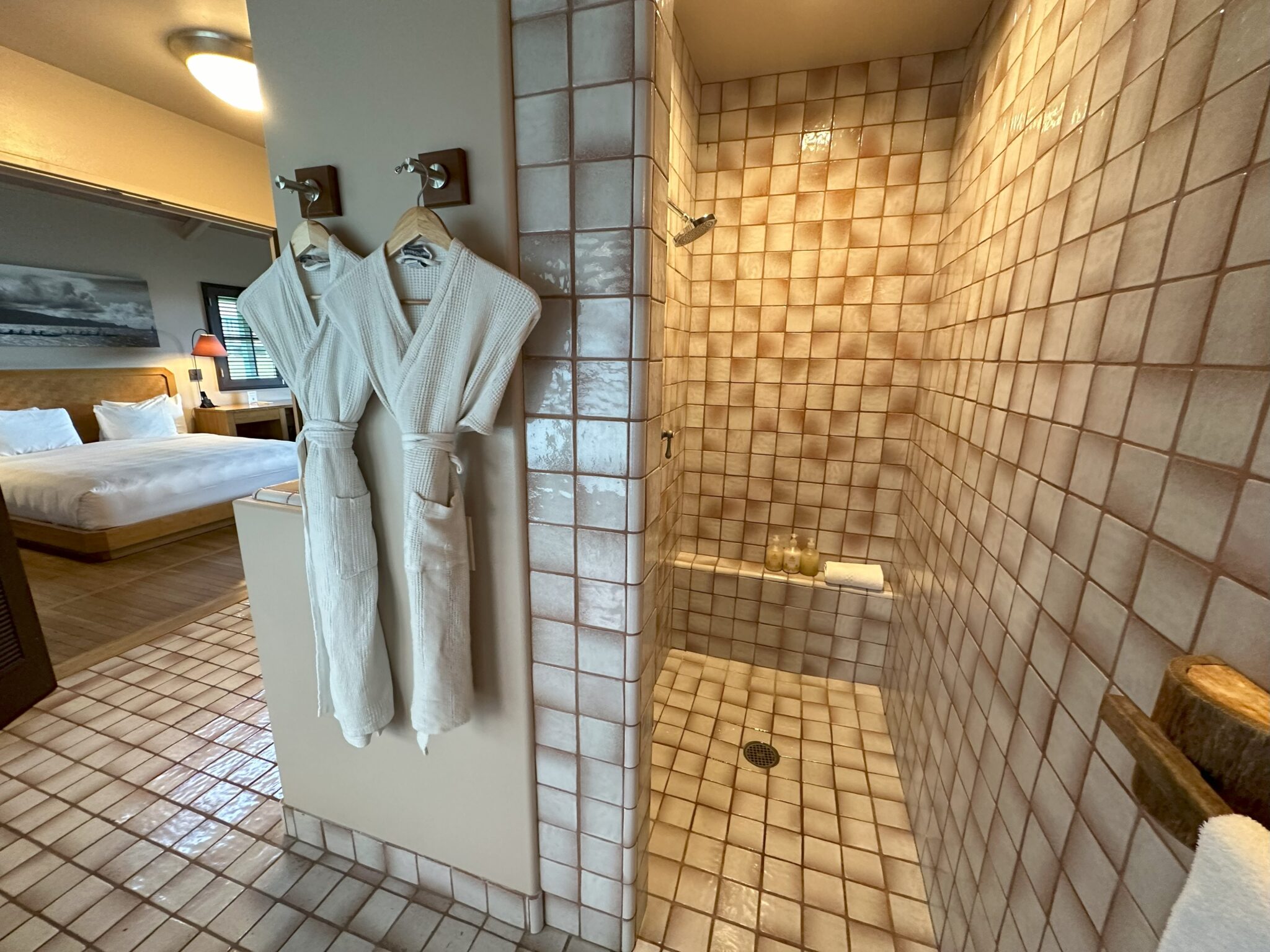 a bathroom with white bathrobes and a shower
