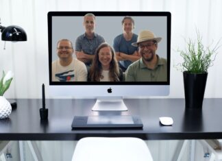 Photo of desk with computer screen on top. The Frequent Miler team is shown on the screen