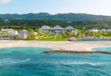 Luxury ocean-side resort hotel with green hills in the background and blue ocean in the foreground