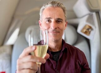 Greg in Emirates first class raising a champagne glass towards the viewer